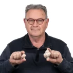 פרופ' צבי קורן מחזיק בקונכיות של ארגמון קהה קוצים. הקטן מודרני והגדול ארכיאולוגי.